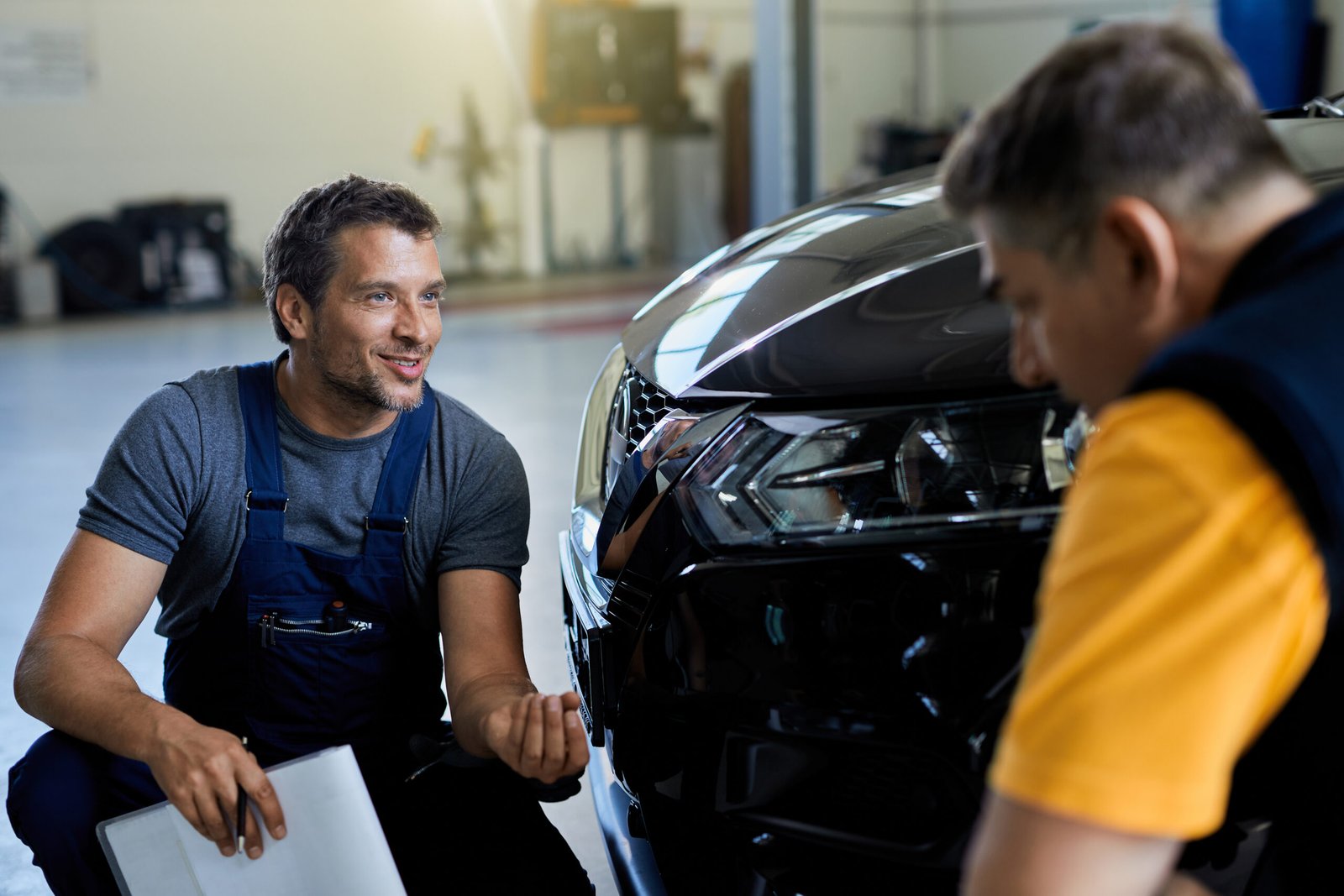 Technician consulting with a customer beside a car in the workshop